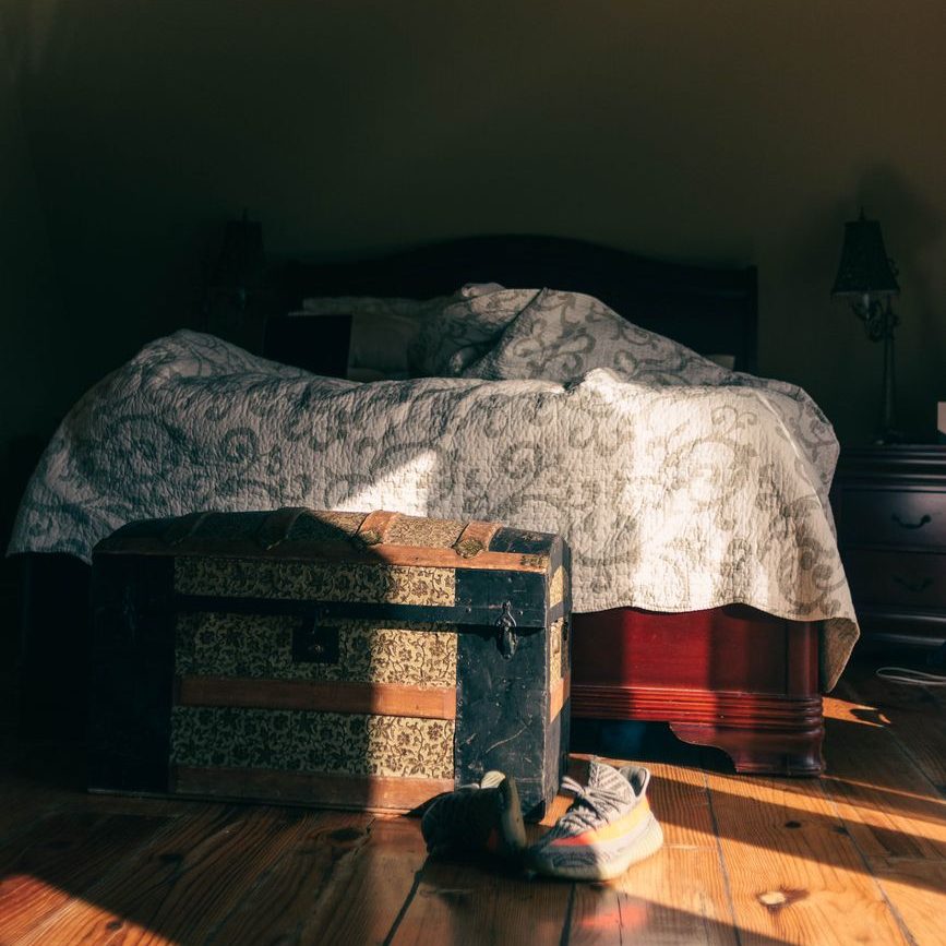 shoes near chest in room with bed